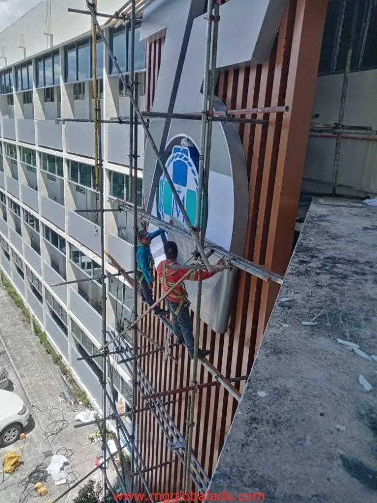 LED signage installation on a multistory building exterior in Ortigas by M&G Global Ads, workers wearing safety harnesses.
