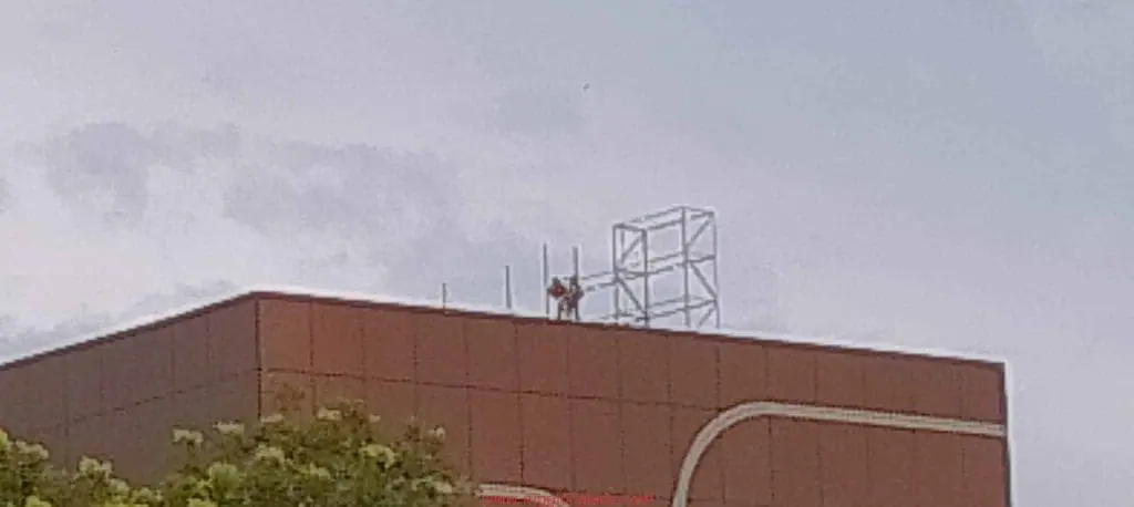 Installation of LED billboard signage framework atop a red building in Makati, cloudy sky, by M&G Global Ads.