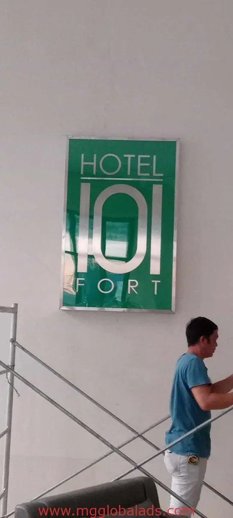 Indoor hotel signage for HOTEL 101 FORT with man by staircase, white wall background in BGC by M&G Global Ads.