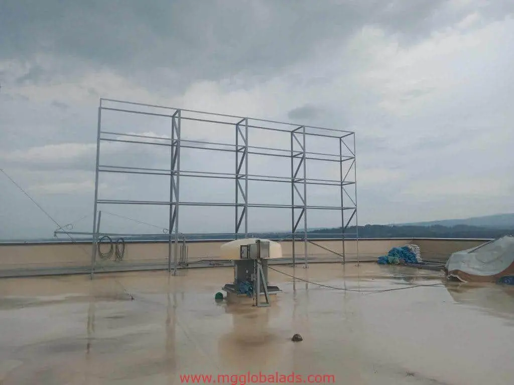 Billboard signage installation on a wet rooftop in Ortigas with acrylic materials and tarps, cloudy sky—by M&G Global Ads.