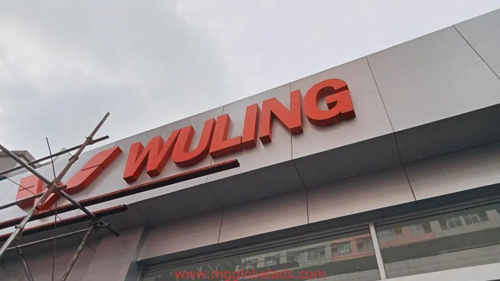 WULING LED signage with large red letters on a modern building in BGC, scaffolding on left. By M&G Global Ads.