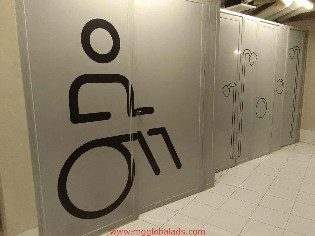 Accessible restroom metallic signage—wheelchair symbol and heart designs—on silver stall doors in Makati by M&G Global Ads.