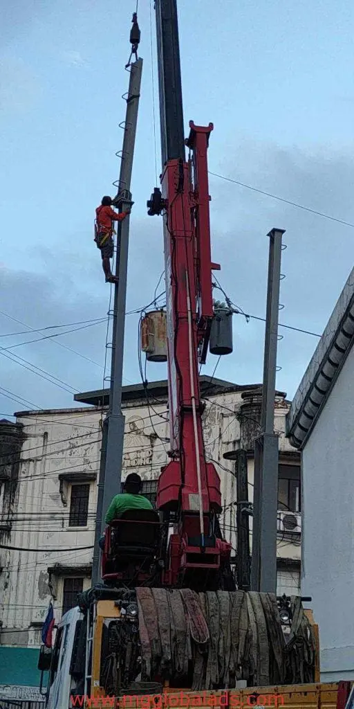Billboard signage installation for commercial client in Quezon City, worker on utility pole with crane, by M&G Global Ads.