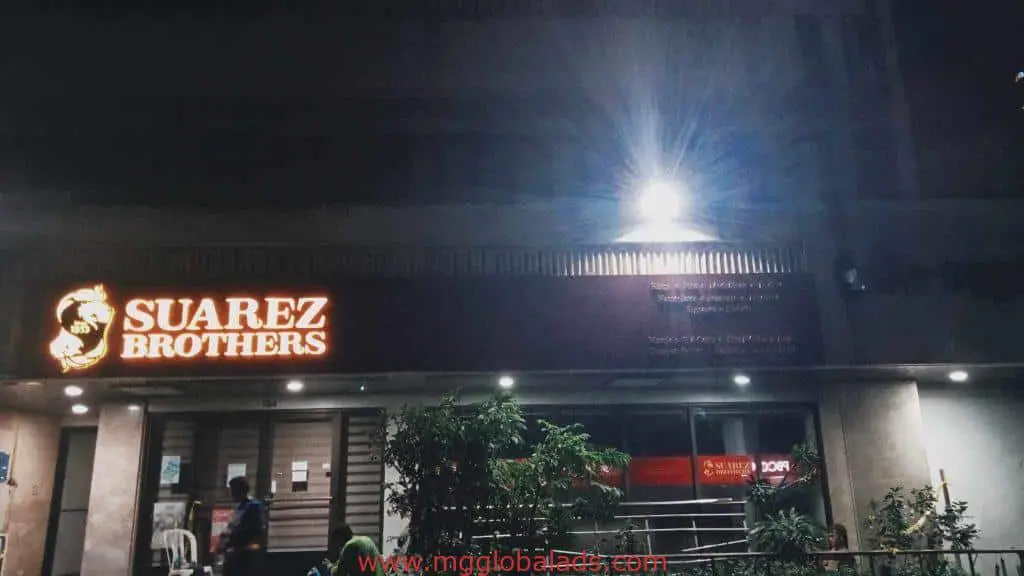 LED building signage for Suarez Brothers at night in Ortigas, plants and people visible outside. By M&G Global Ads.
