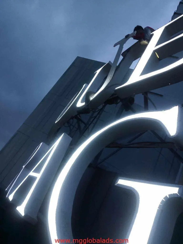 LED outdoor signage installation with white neon letters in Ortigas at dusk, viewed from below, by M&G Global Ads.
