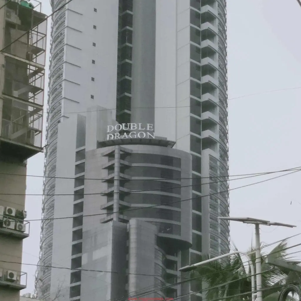 Outdoor DOUBLE DRAGON building signage in Makati on a tall modern tower with curved balconies, by M&G Global Ads.