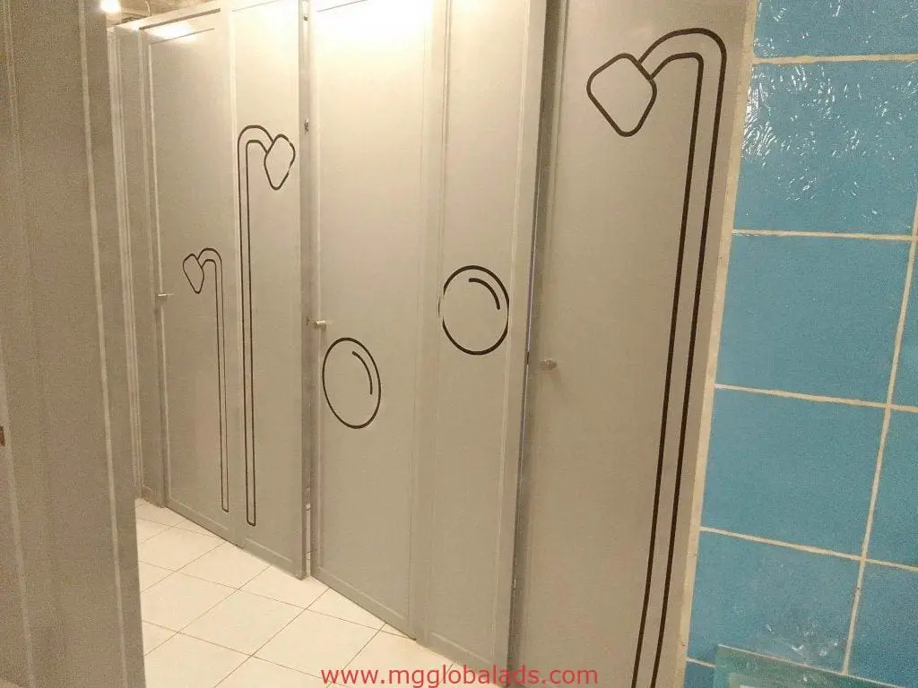 Metallic bathroom signage, showerhead and soap icon decals in Makati public restroom with tiled walls and floor by M&G Global Ads.