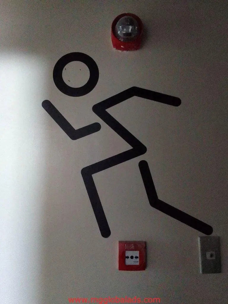 LED emergency signage with stick figure running toward fire alarms in Makati, red alarm above, by M&G Global Ads.