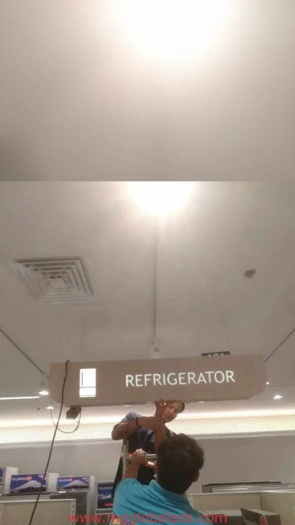 Ceiling-mounted acrylic signage installation labeled REFRIGERATOR in a Makati store, building signs visible, by M&G Global Ads.