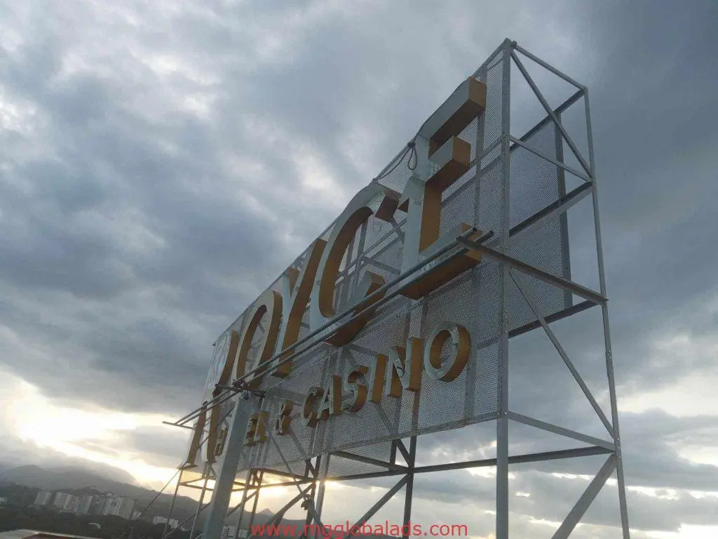 Metallic hotel and casino signage for JOYCE, Quezon City skyline at sunset, by M&G Global Ads.