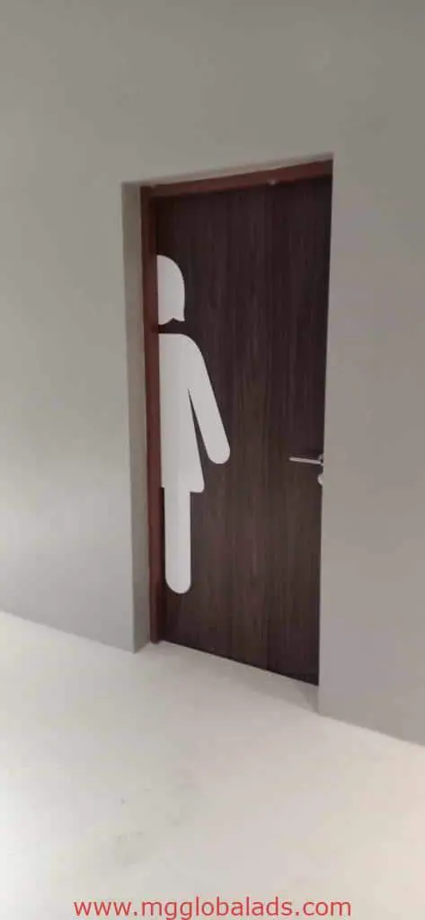 Metallic womens restroom signage on a dark brown door, partly cut off, in Makati office hallway by M&G Global Ads.