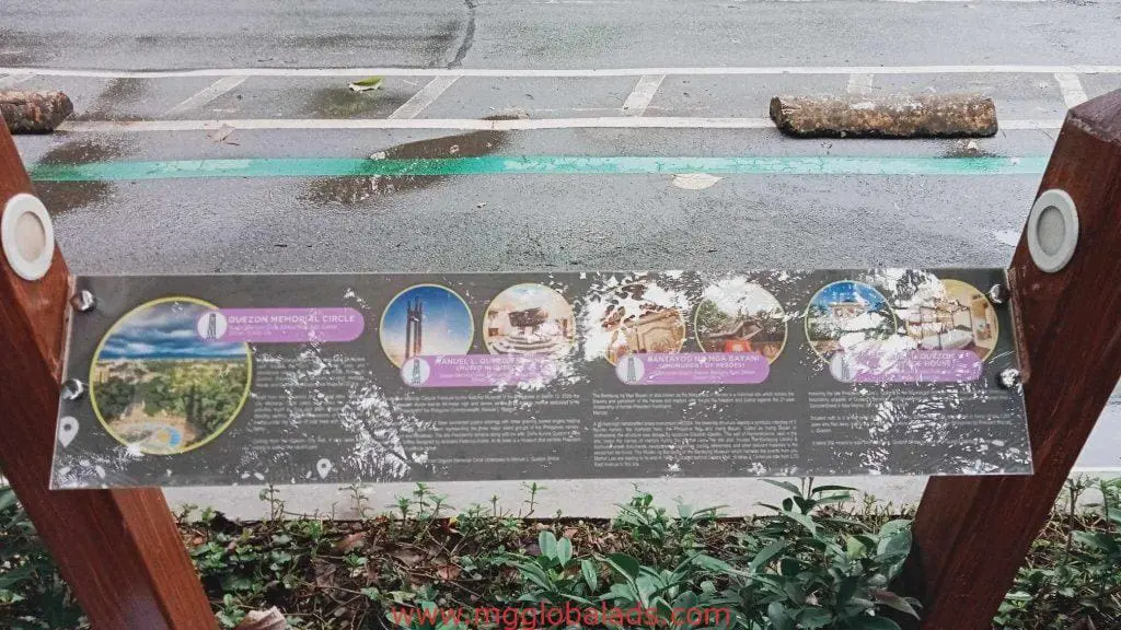 Outdoor directional signage in Quezon City, weathered and mounted on wooden posts near bike lane, by M&G Global Ads.