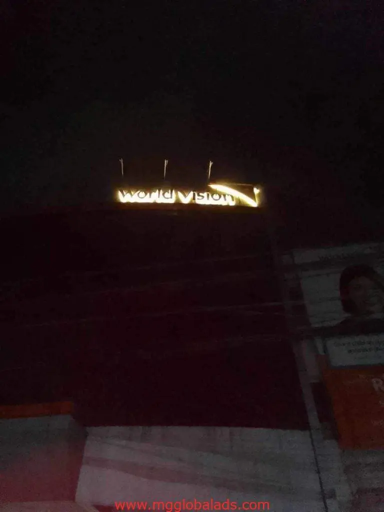 World Vision acrylic rooftop signage lighting up a Makati building at night, some letters dim. By M&G Global Ads.