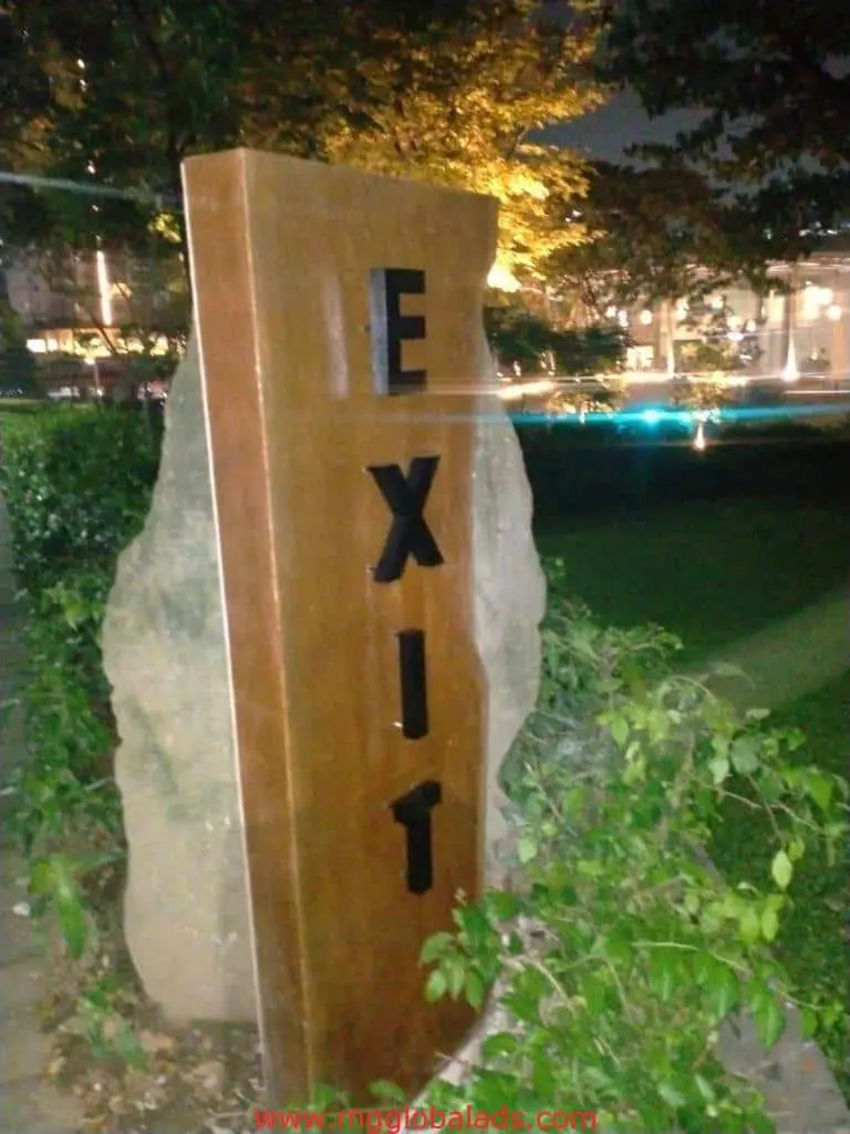 Outdoor EXIT sign, rectangular pylon signage near greenery at night in Quezon City, illuminated by lights, by M&G Global Ads.