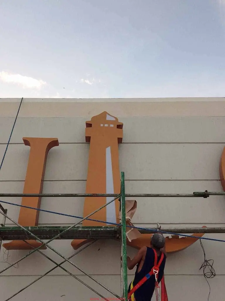 Acrylic letter L signage installation on building facade in Makati, under partly cloudy sky by M&G Global Ads.