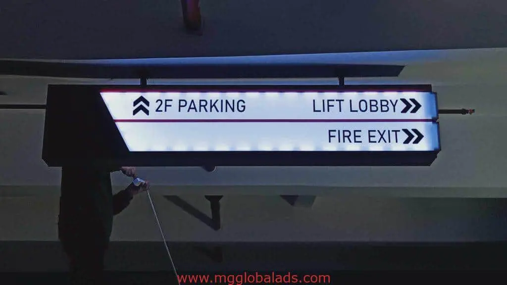 LED ceiling signage in a Quezon City parking garage shows directions near a person with white cane. By M&G Global Ads.
