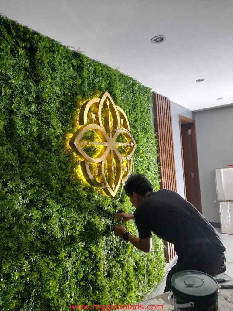 LED illuminated signage installation on artificial plant wall in a modern Mandaluyong building interior by M&G Global Ads.