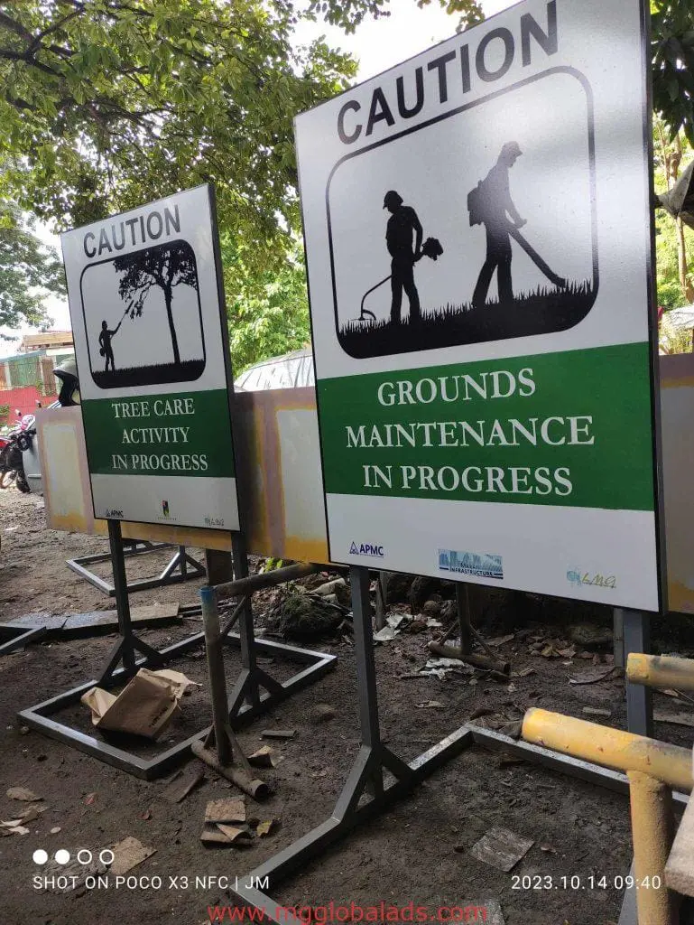 Metallic safety signage for tree and grounds maintenance in Quezon City by M&G Global Ads, outdoors, workers tending trees.
