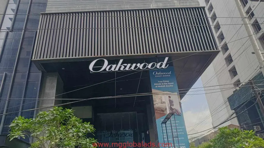 Oakwood metallic entrance signage, vertical banner, and outdoor signs on modern building in Makati by M&G Global Ads.