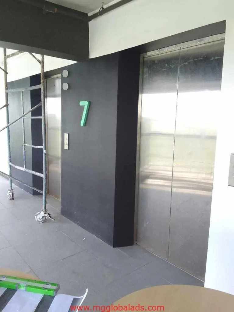 Sleek acrylic number 7 wall signage in a modern Makati building corridor with elevators and scaffolding by M&G Global Ads.