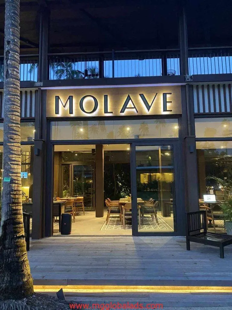 Building signage for MOLAVE restaurant in Makati, with glass windows, wood decor, outdoor seating at dusk by M&G Global Ads.