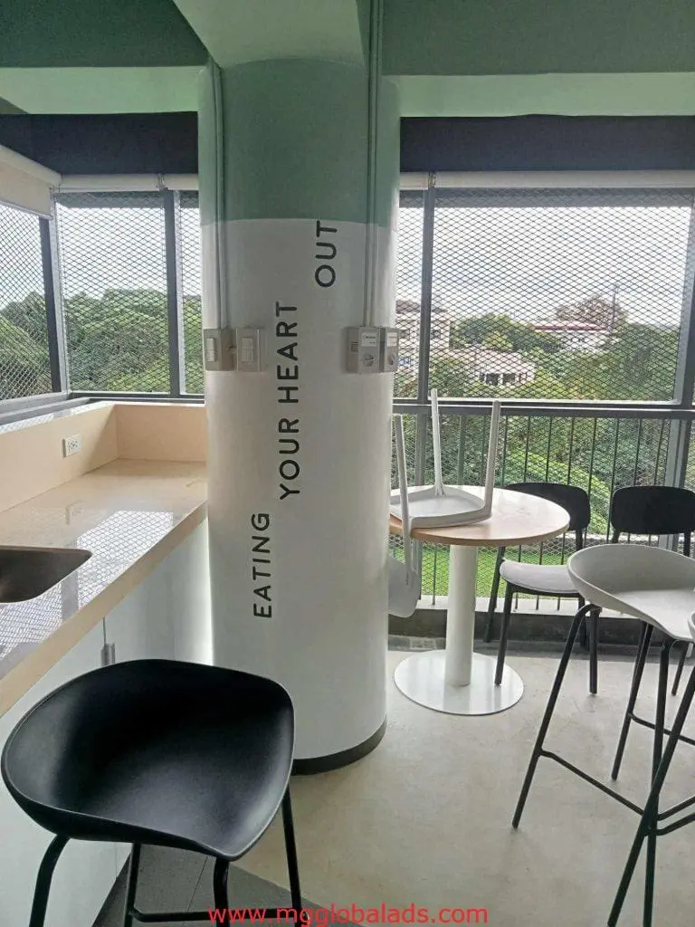 Indoor lighted signage “EATING YOUR HEART OUT” in stylish dining area, with city views in Makati, by M&G Global Ads.