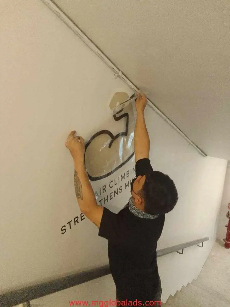 Acrylic signage wheelchair accessibility decal installed on a wall atop stairs in Ortigas, ironically inaccessible, by M&G Global Ads.