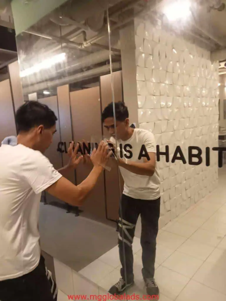 LED signage cleaning at modern restroom glass wall, IS A HABIT text, Quezon City installation by M&G Global Ads.