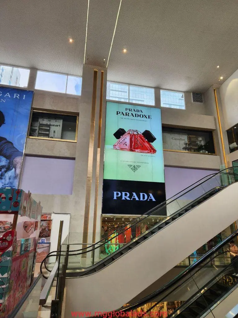 Prada LED signage ad in Makati mall with red Prada Paradoxe perfume bottle above escalators, by M&G Global Ads.