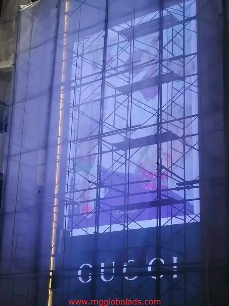 Illuminated Gucci outdoor signage on a building facade with scaffolding in Makati, Metro Manila by M&G Global Ads.