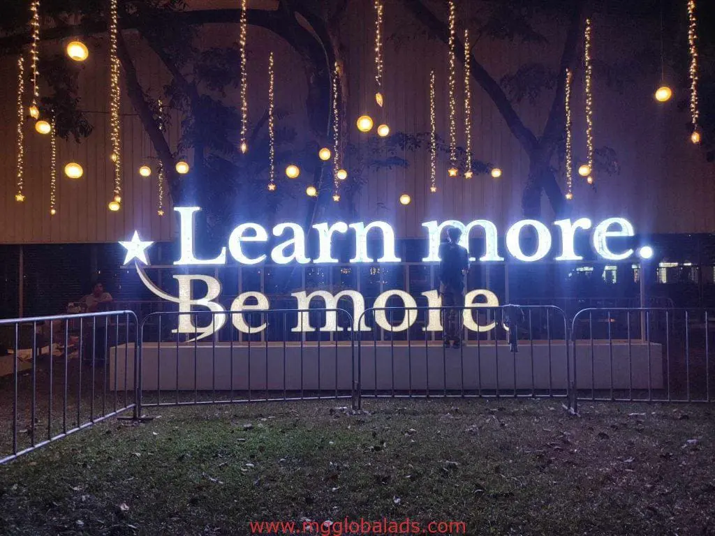 LED signage in Makati displaying Learn more. Be more at night with festive lights and trees, by M&G Global Ads.
