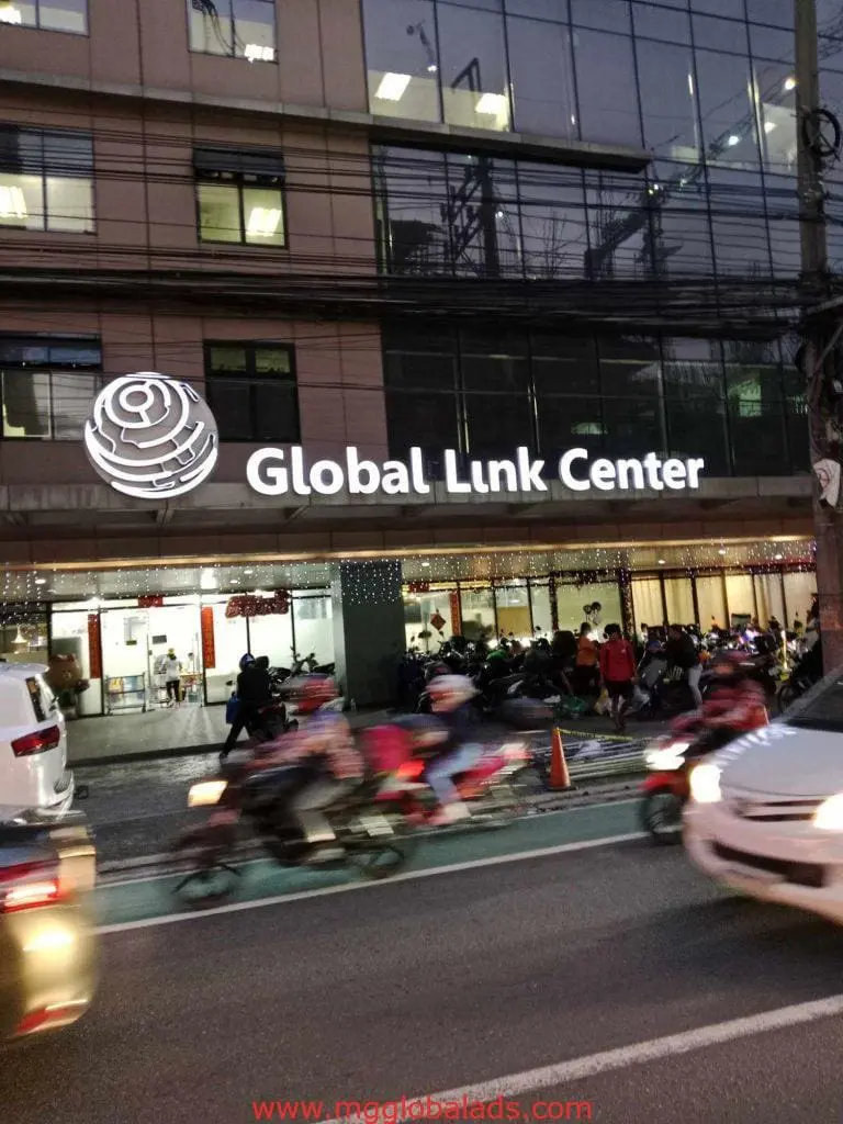 Metallic Global Link Center building signage in Makati, with traffic and pedestrians visible, by M&G Global Ads.