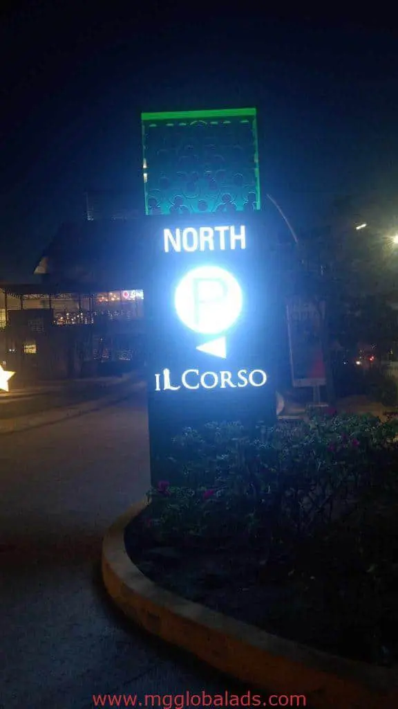 Illuminated metallic pylon signage for IL CORSO with NORTH and parking symbol at night in BGC by M&G Global Ads.
