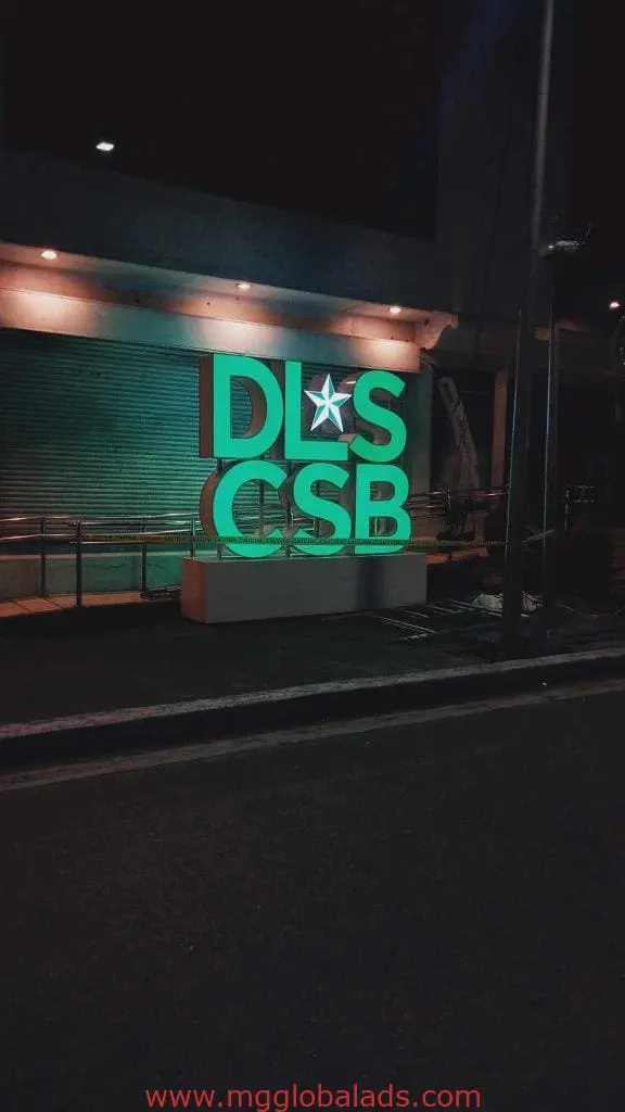 Illuminated acrylic DLS CSB signage with star glows green at night in Makati, outdoor building sign by M&G Global Ads.