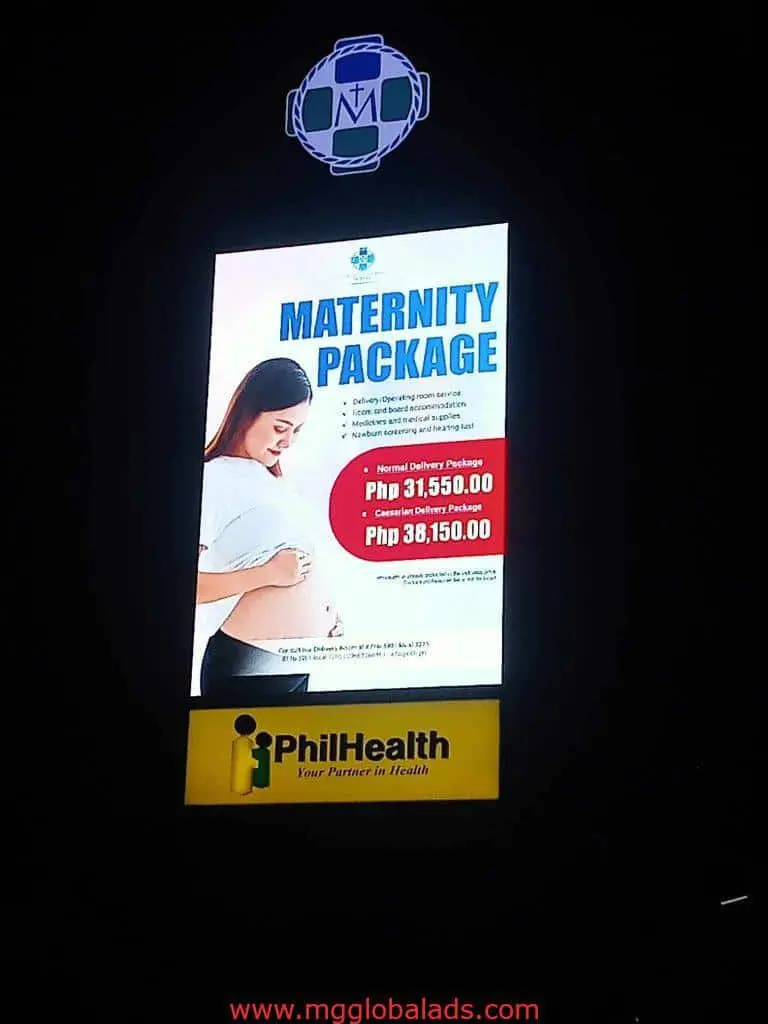 Digital LED signage in Makati shows a PhilHealth Maternity Package ad, pricing, and slogan at night by M&G Global Ads.