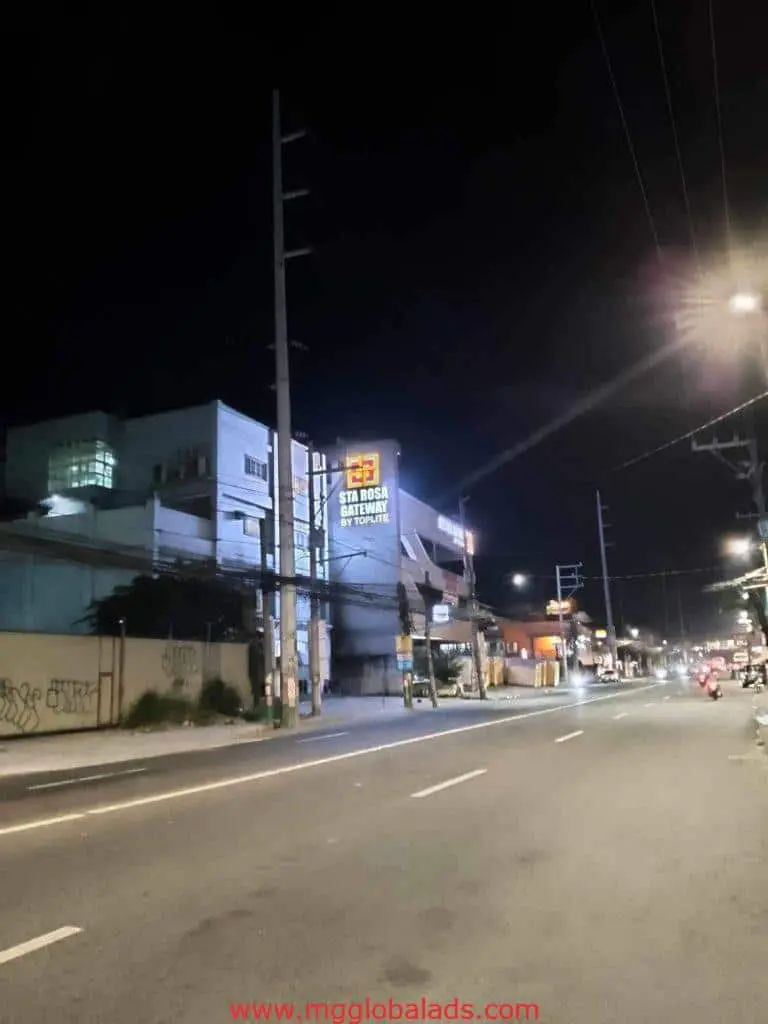 Hotel signage for RedDoorz Star Rossa Royse Batanes in Makati at night, bright lights, empty street by M&G Global Ads.