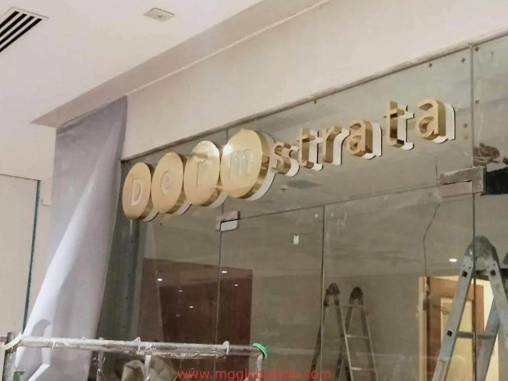Storefront metallic signage installation for Demstrata in BGC, with ladder and materials visible, by M&G Global Ads.