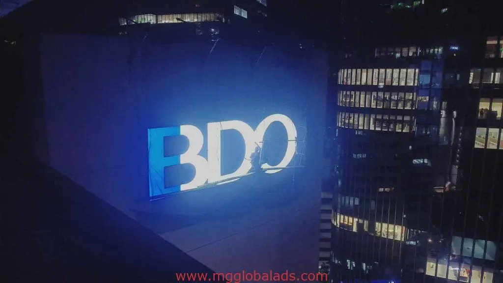 BDO LED signage on building exterior at night in Makati, city light reflections, by M&G Global Ads.