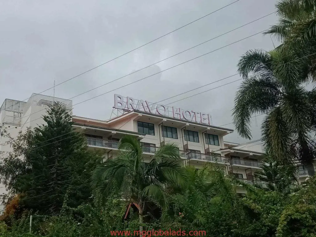Metallic outdoor hotel signage for BRAVO HOTEL on building in Makati with palm trees and power lines by M&G Global Ads.