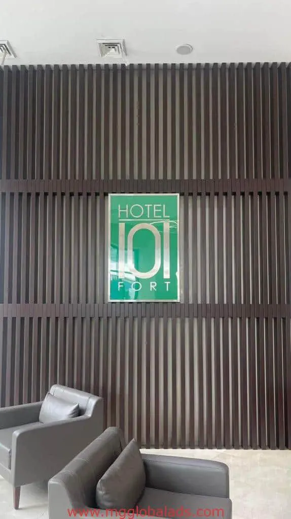 Green acrylic hotel signage for Hotel 101 at Fort, Makati, with wood wall panels and gray chairs by M&G Global Ads.
