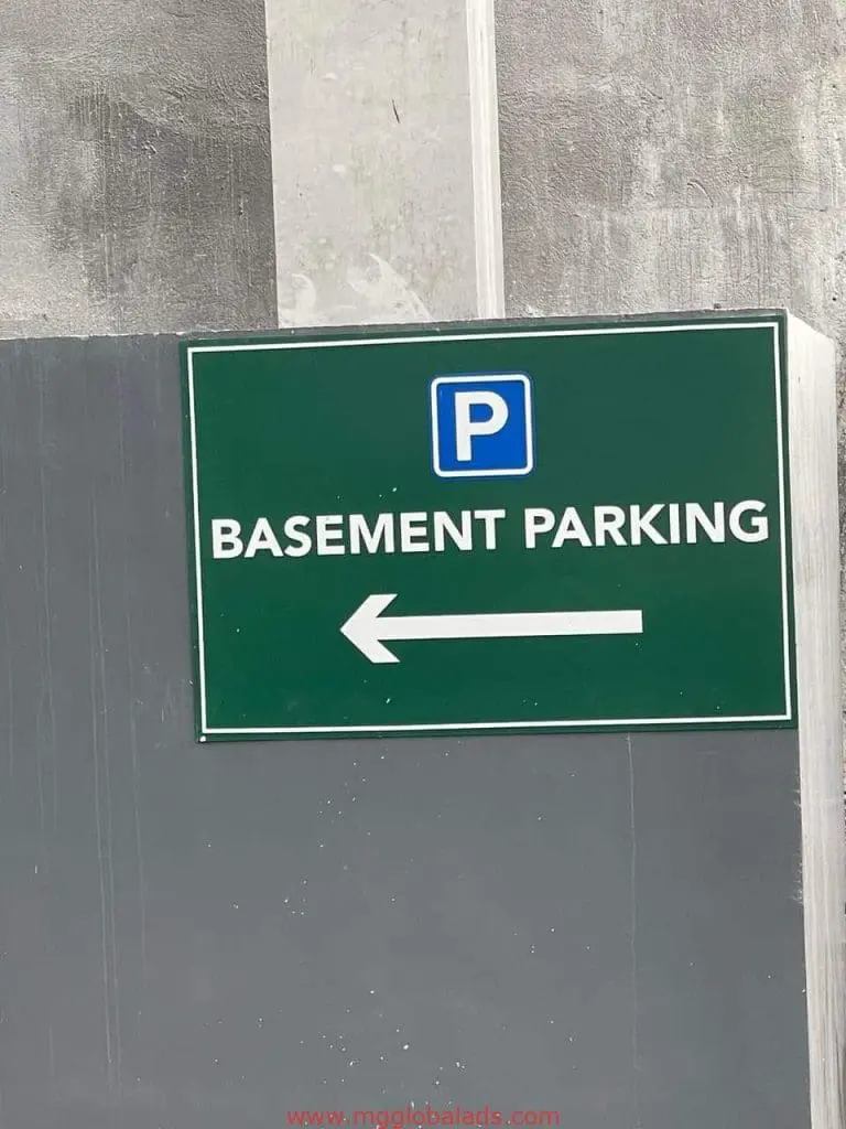 Outdoor basement parking directional signage with white arrow in Makati, mounted on gray wall by M&G Global Ads.