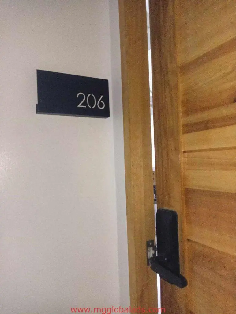 Acrylic indoor room signage 206, white on black, beside a wooden door in Makati condominium interior by M&G Global Ads.