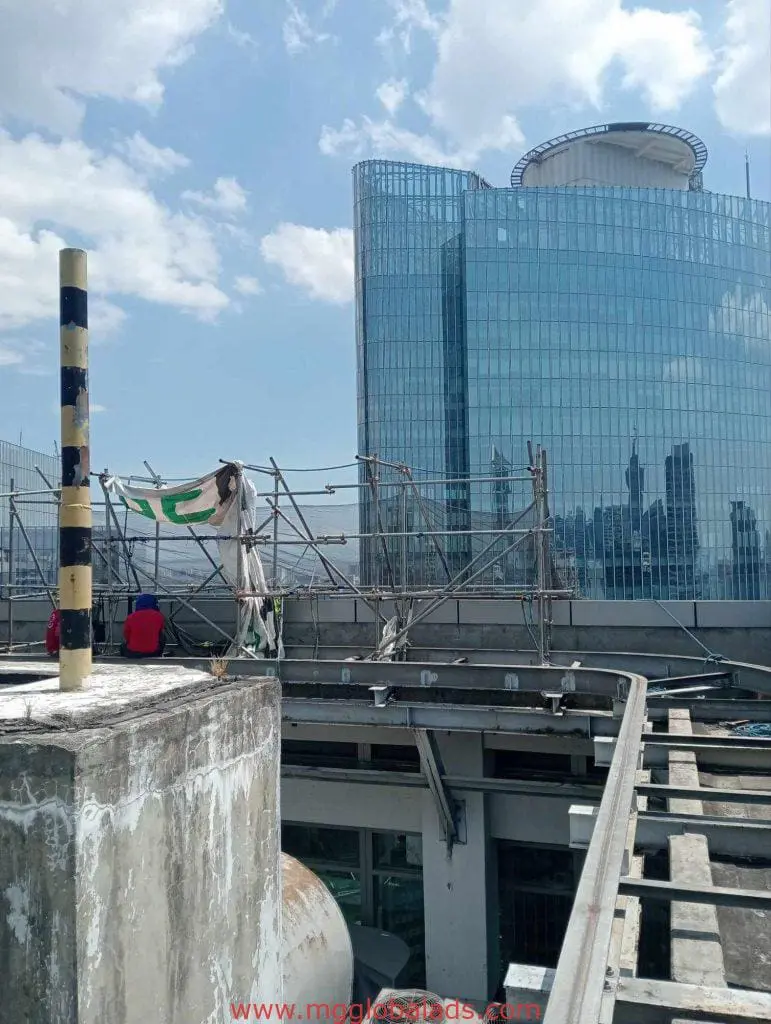 Workers install outdoor LED signage on a rooftop in Makati with skyscraper background, by M&G Global Ads.