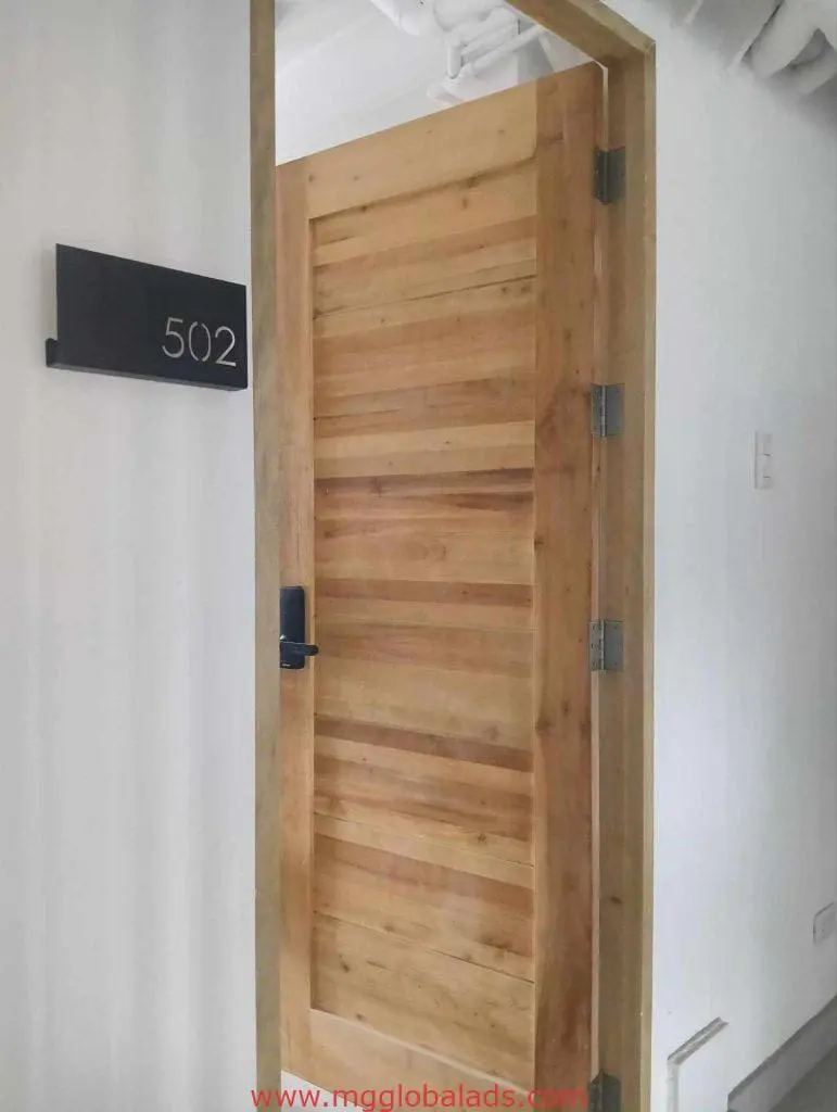 Metallic room number sign 502 on wooden door, hallway view with ceiling pipes, office signage Makati by M&G Global Ads.