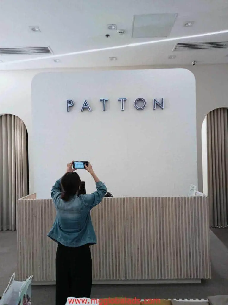 PATTON illuminated indoor signage at a modern reception desk in Makati, person taking photo, by M&G Global Ads.