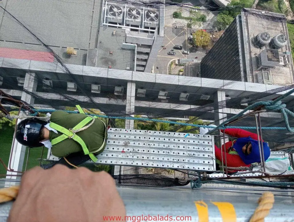 Billboard installation for commercial client in Makati with two workers on suspended platform, by M&G Global Ads.