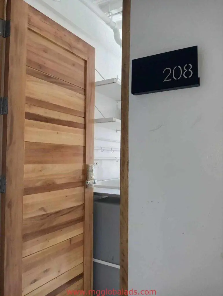 Acrylic room signage 208 on a white wall next to a wooden door in an Ortigas office storage by M&G Global Ads.