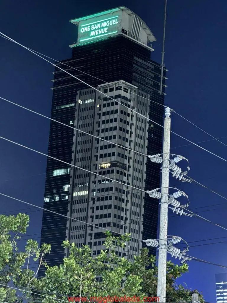 LED building signage for One San Miguel Avenue in Ortigas, illuminated at night with streetlight and trees, by M&G Global Ads.