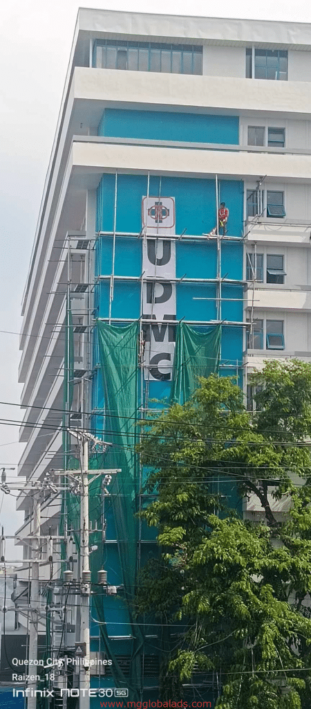 Vertical hospital signage installation for UPMC on a tall white and blue building in Quezon City by M&G Global Ads.