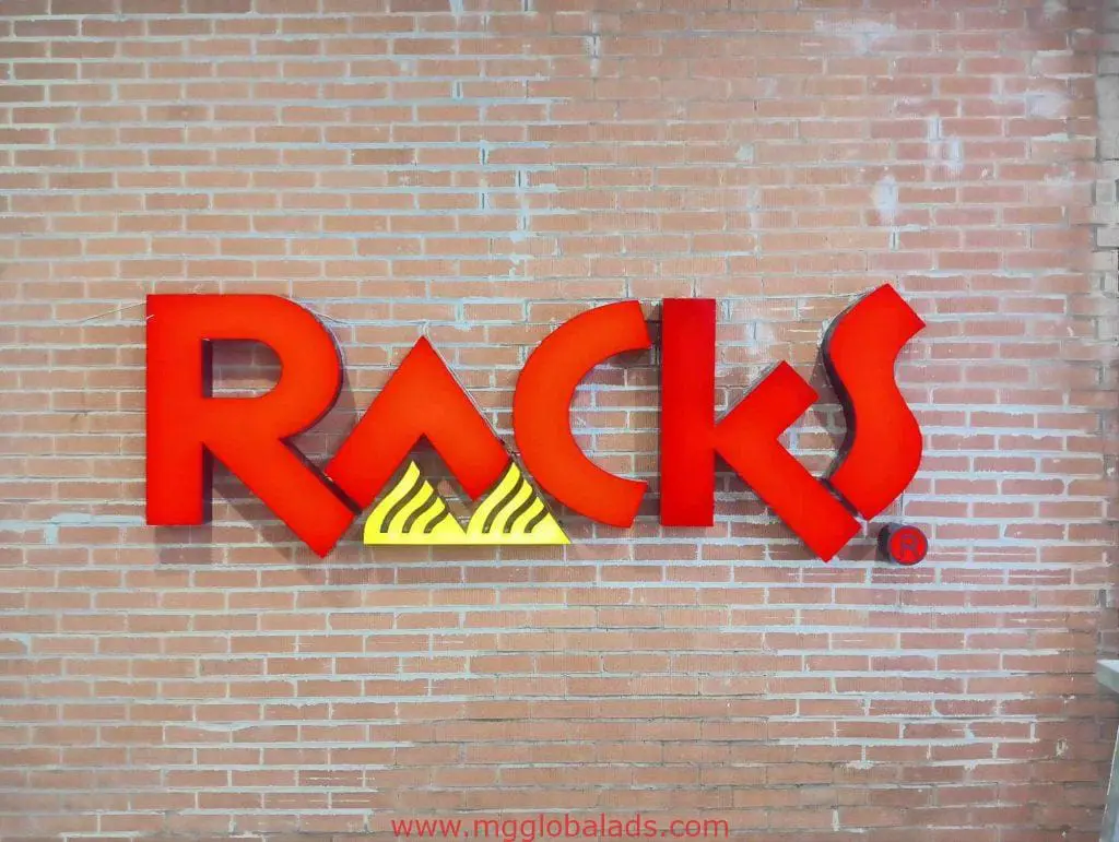 Red Racks metallic business sign with yellow triangle A on brick wall in Ortigas, creative signage by M&G Global Ads.
